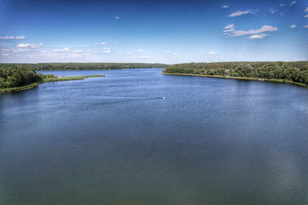 Mazury — widok z lotu ptaka na jezioro otoczone lasem